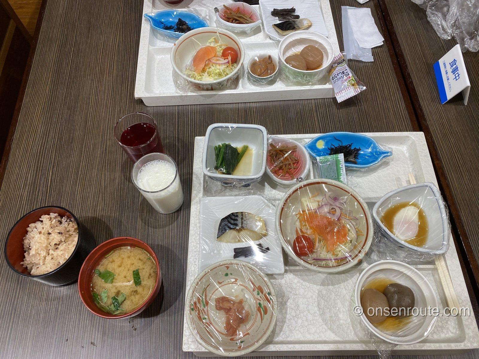 朝食の和定食。焼き魚・サラダ・温泉卵・こんにゃくなどの小鉢がトレーに並ぶ