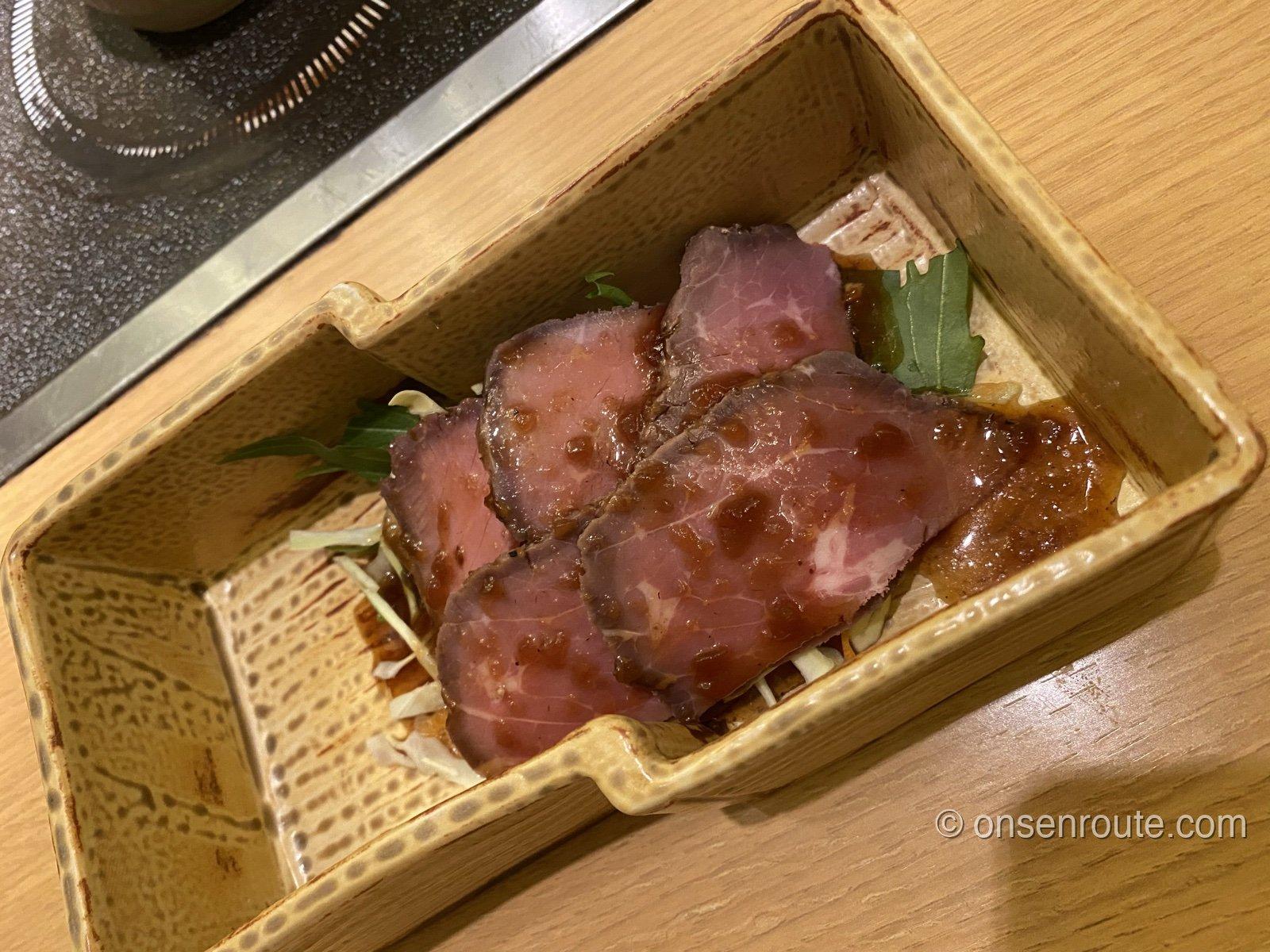 夕食のローストビーフ。ソースのかかったスライスが器に盛られている