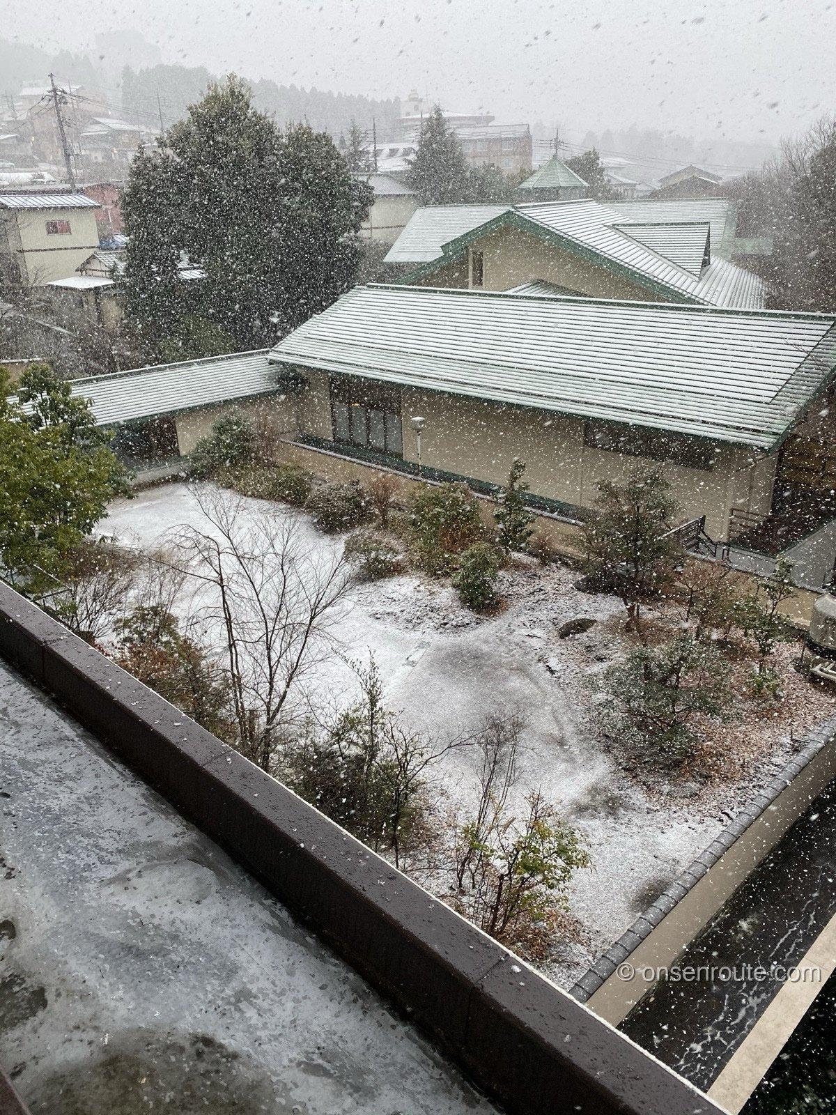 部屋の窓から見下ろした雪の降る中庭と宿の屋根