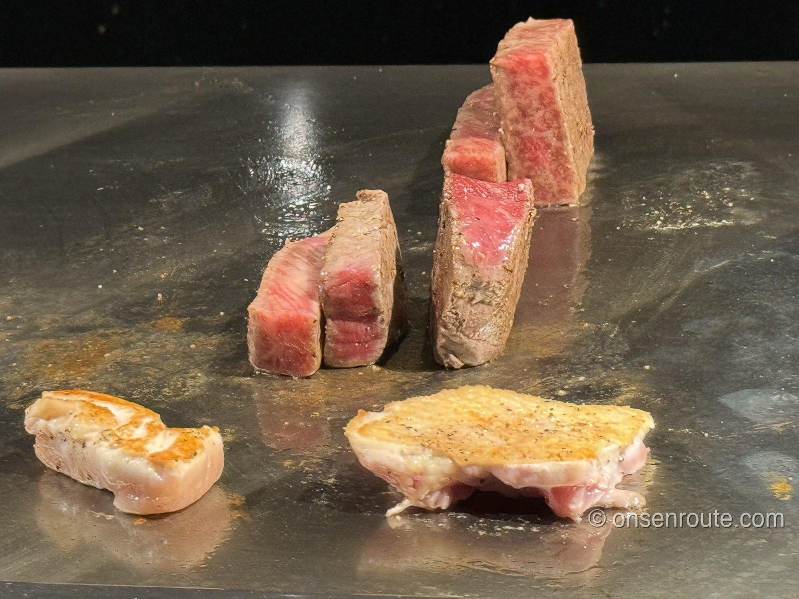 鉄板の上で焼かれる厚切りの牛肉と魚介