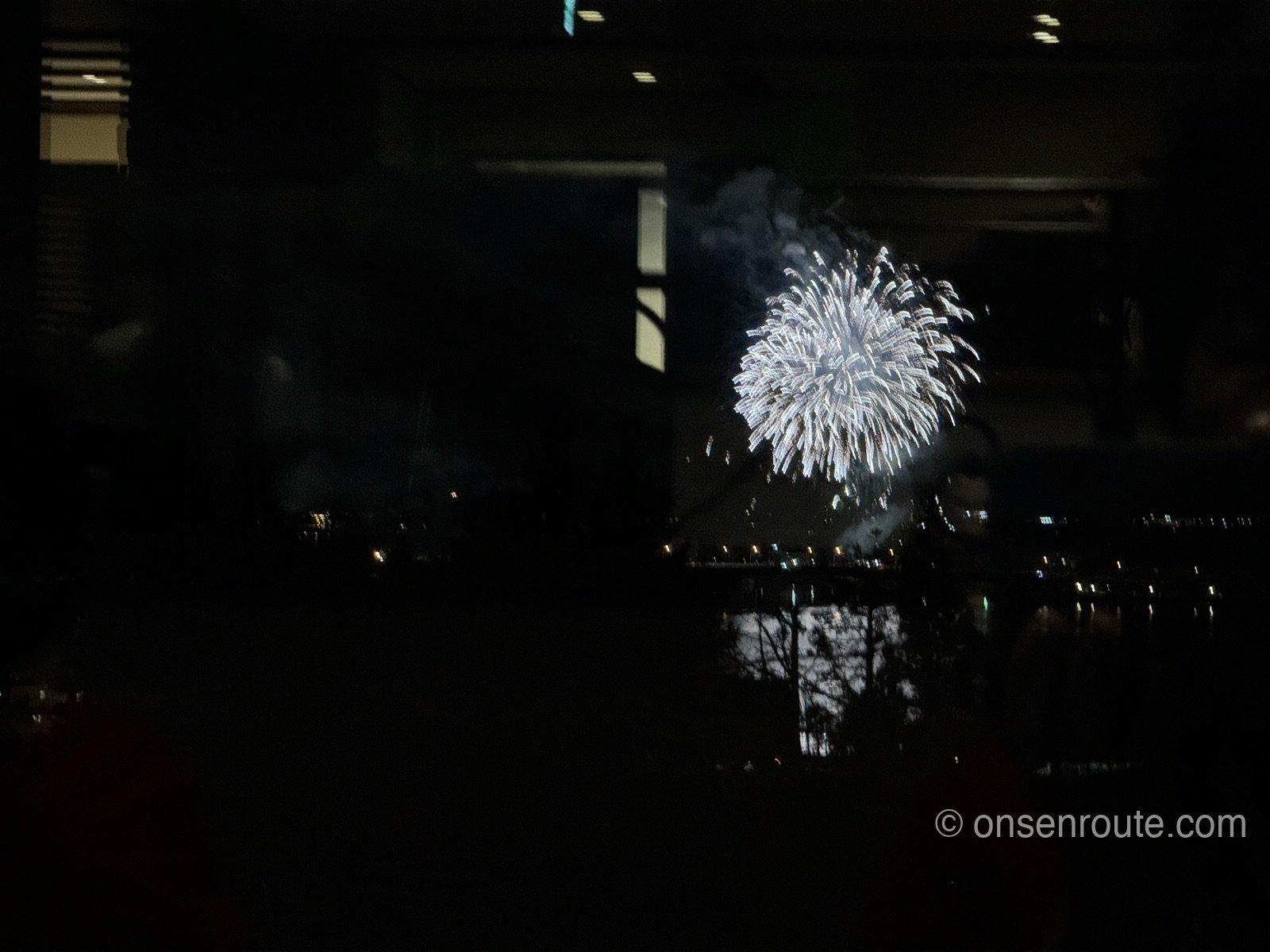 レストランの窓越しに見える河口湖の冬花火。湖面に白い花火の光が映る