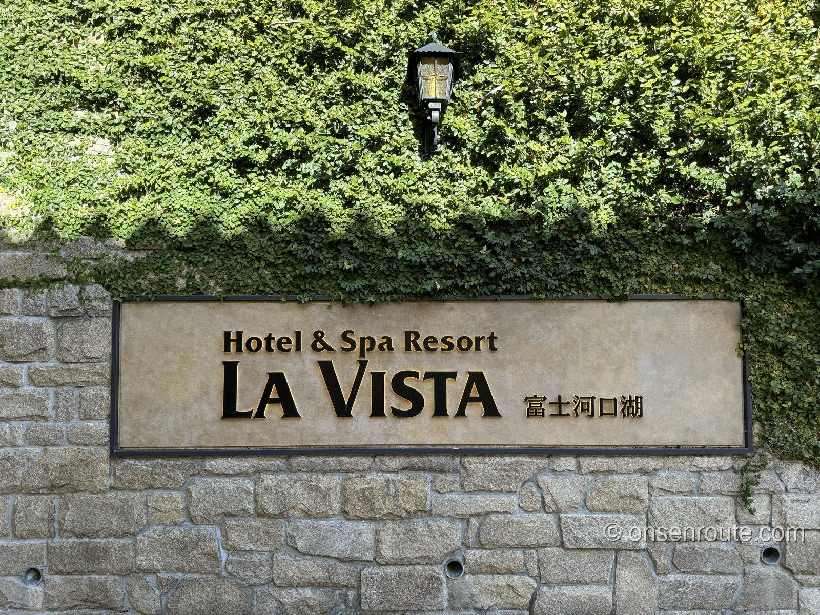石壁に掲げられたHotel & Spa Resort LA VISTA 富士河口湖の看板。上部を蔦の緑が覆う