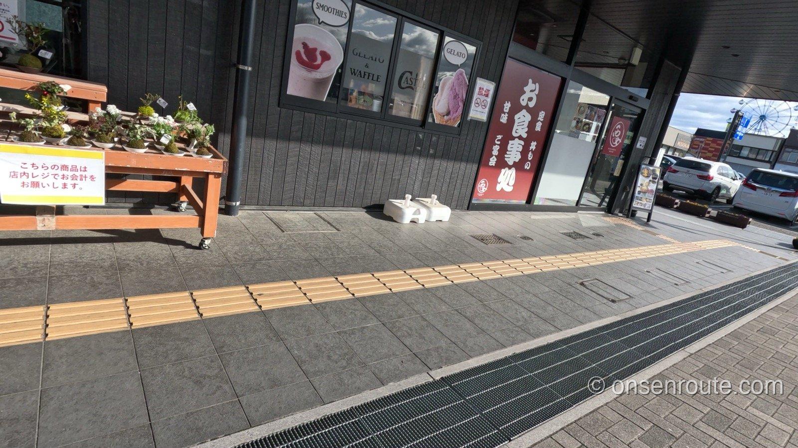 道の駅日光 日光街道ニコニコ本陣の入口。お食事処の看板とジェラート店の窓、店頭の鉢植えが並ぶ