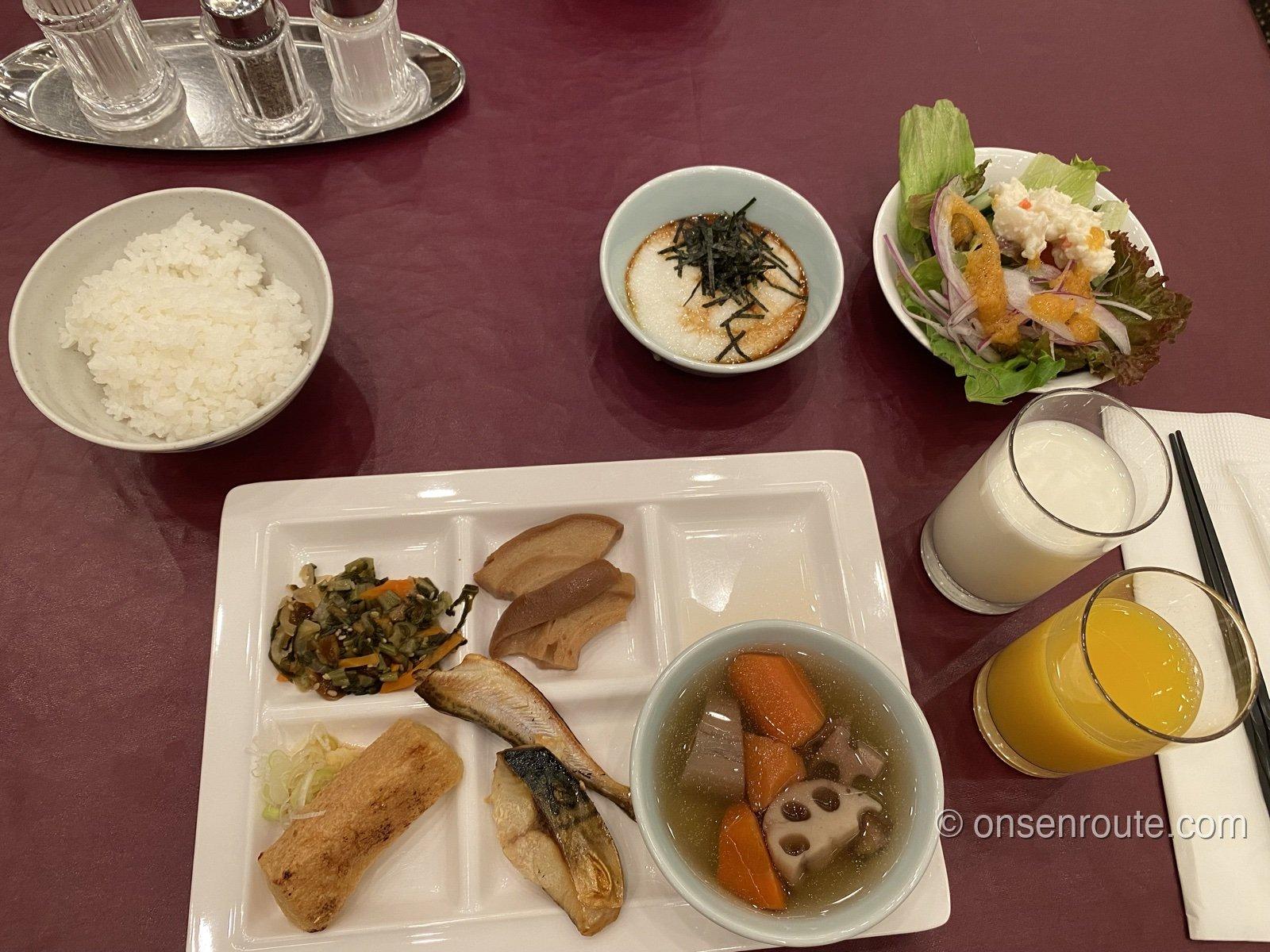 朝食ビュッフェの盛り付け。白飯、とろろ、焼き魚、煮物、サラダ、ジュースが並ぶ
