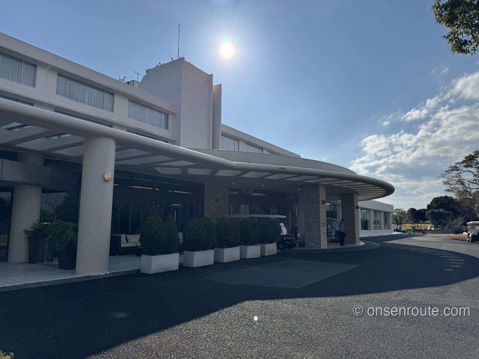 NEMU RESORTのホテル棟の車寄せ。白い大きな屋根の下に丸く刈り込まれた植栽が並び、奥に白い建物が見える
