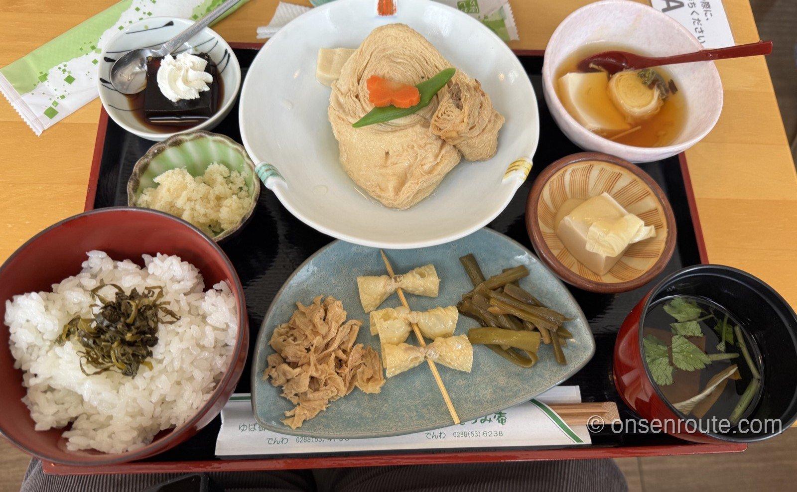 湯波御膳のお膳。福ゆばの煮物を中心に、ゆばの佃煮や串ゆば、酢の物など小鉢が並ぶ