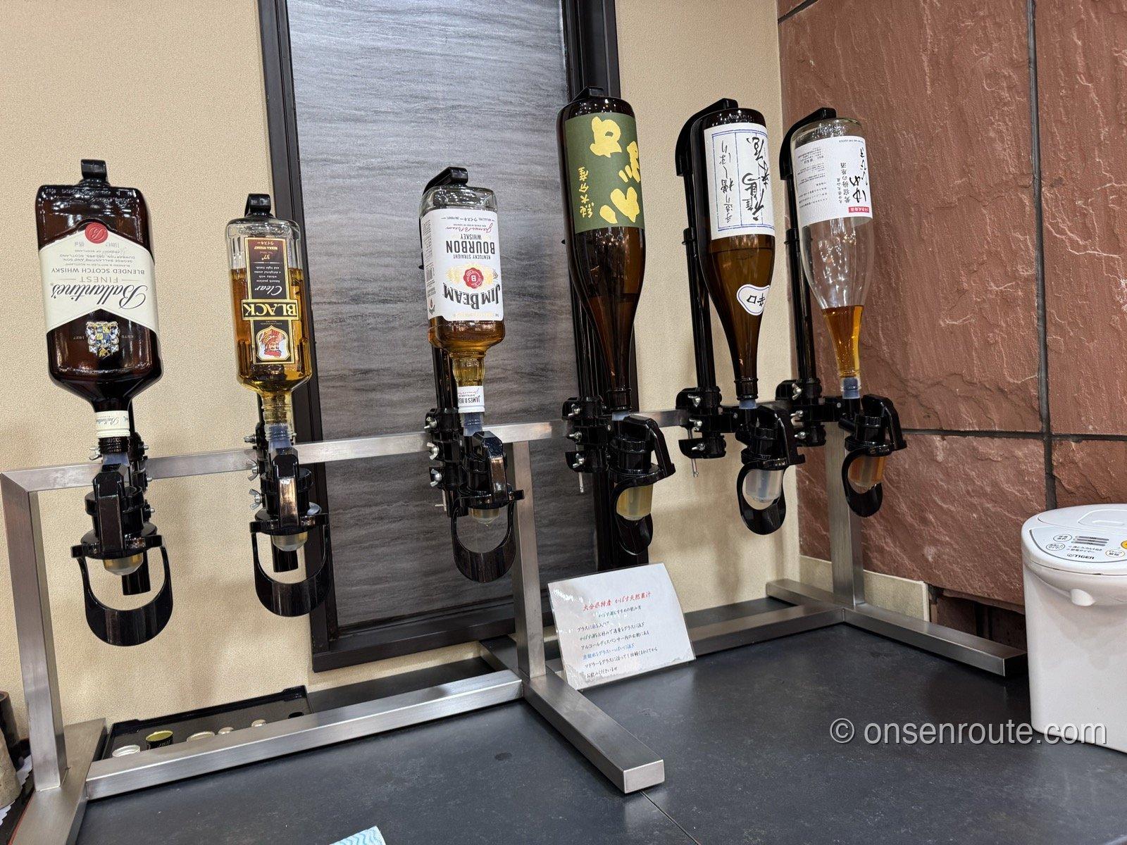 ウイスキーと日本酒のボトルディスペンサーが並ぶコーナー。バランタイン、ジムビームなどが逆さに設置されている