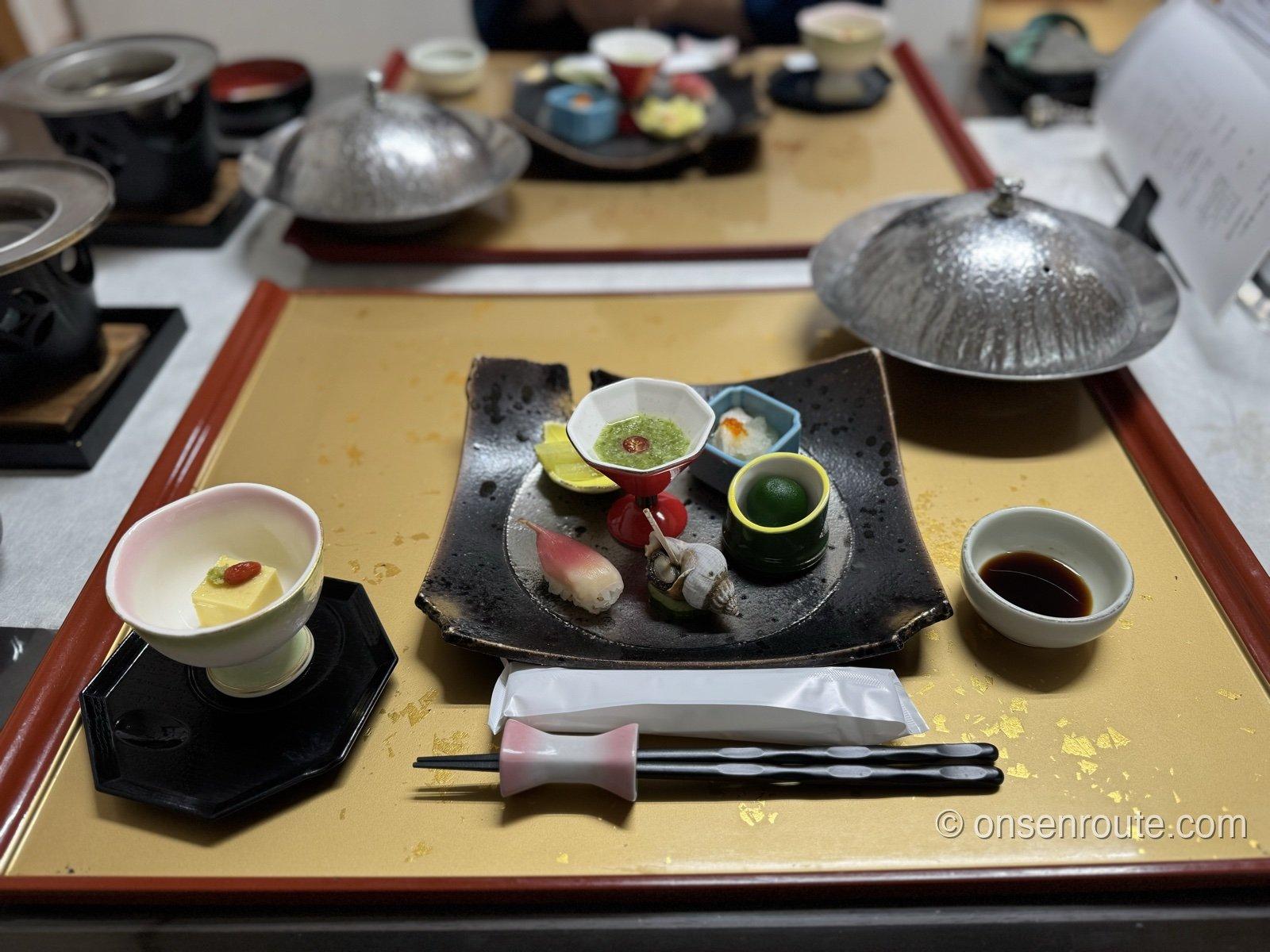 旅籠しび荘の夕食。前菜の盛り合わせと火にかける鍋が並ぶ