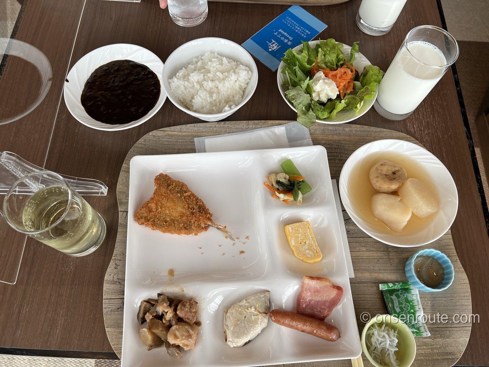 朝食ビュッフェの盛り付け。アジフライ、卵焼き、おでん、しらす、サラダ、カレーが並ぶ