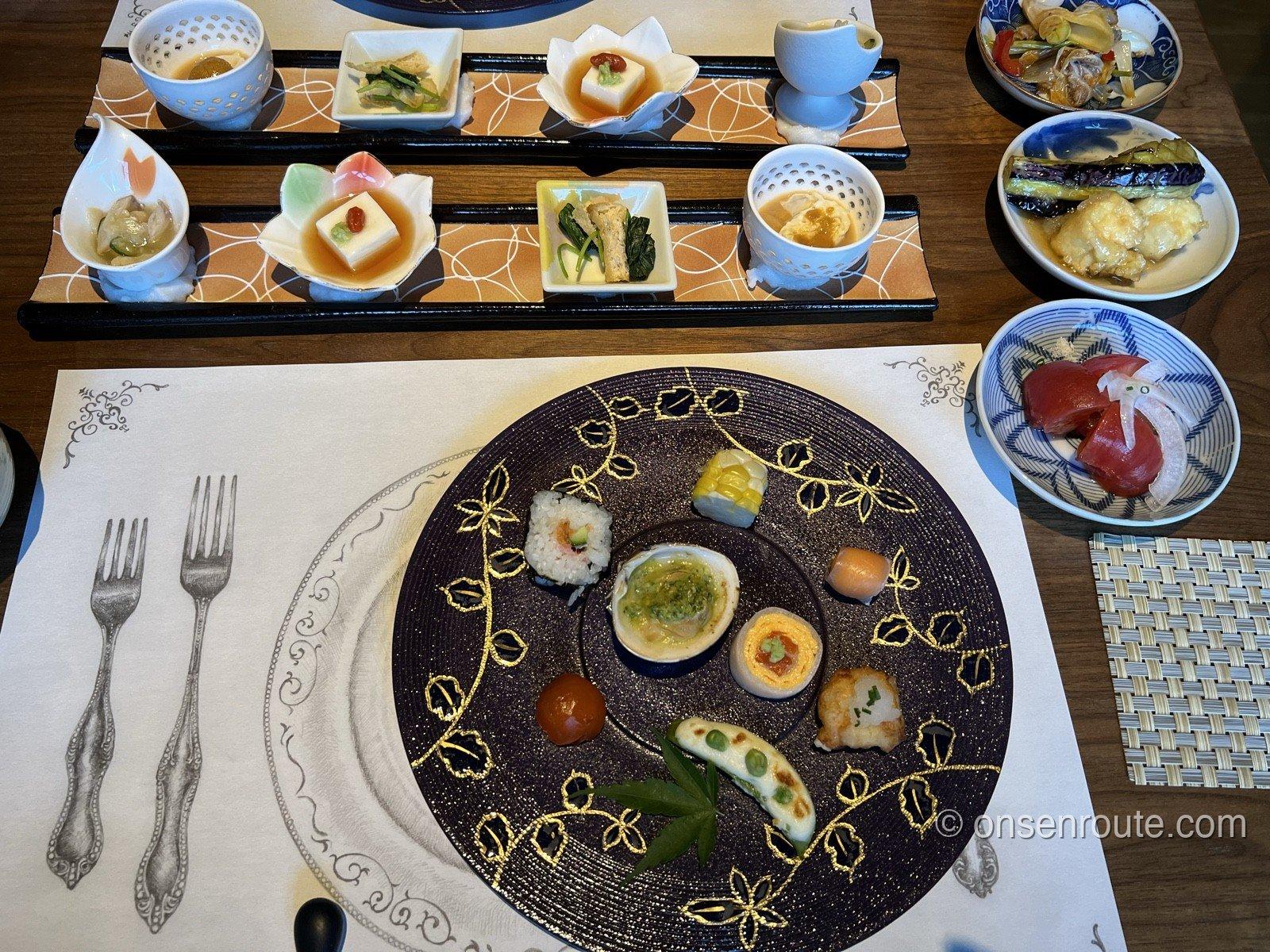 山風木の夕食の前菜。金彩の飾り皿に巻き寿司、はまぐり、卵、とうもろこしなどが一口ずつ盛られ、奥の膳に茶碗蒸しや豆腐の小鉢が並ぶ