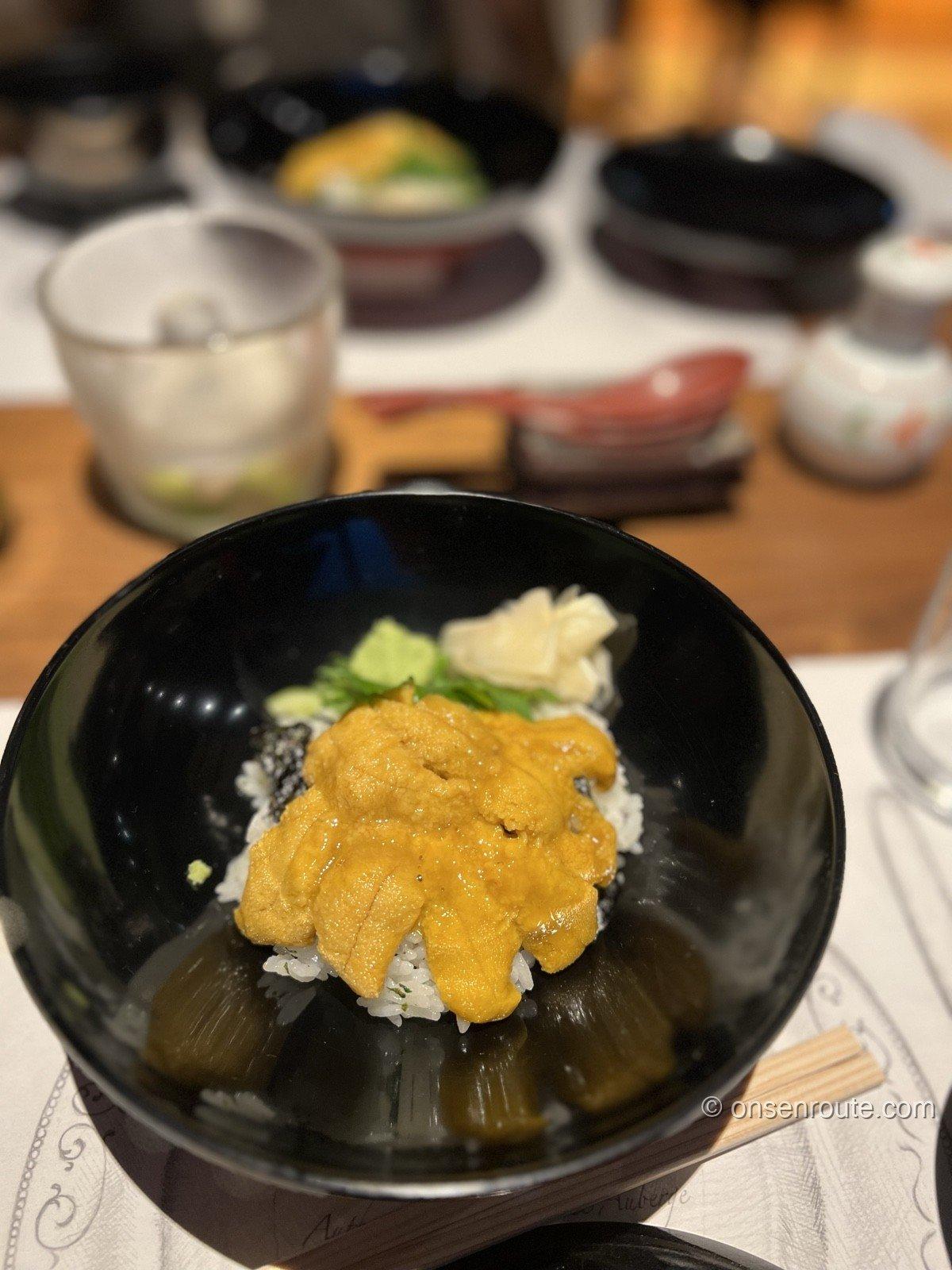 黒い椀に盛られた生雲丹丼。白飯と海苔の上にオレンジ色の生雲丹が敷き詰められ、大葉とガリ、わさびが添えられている