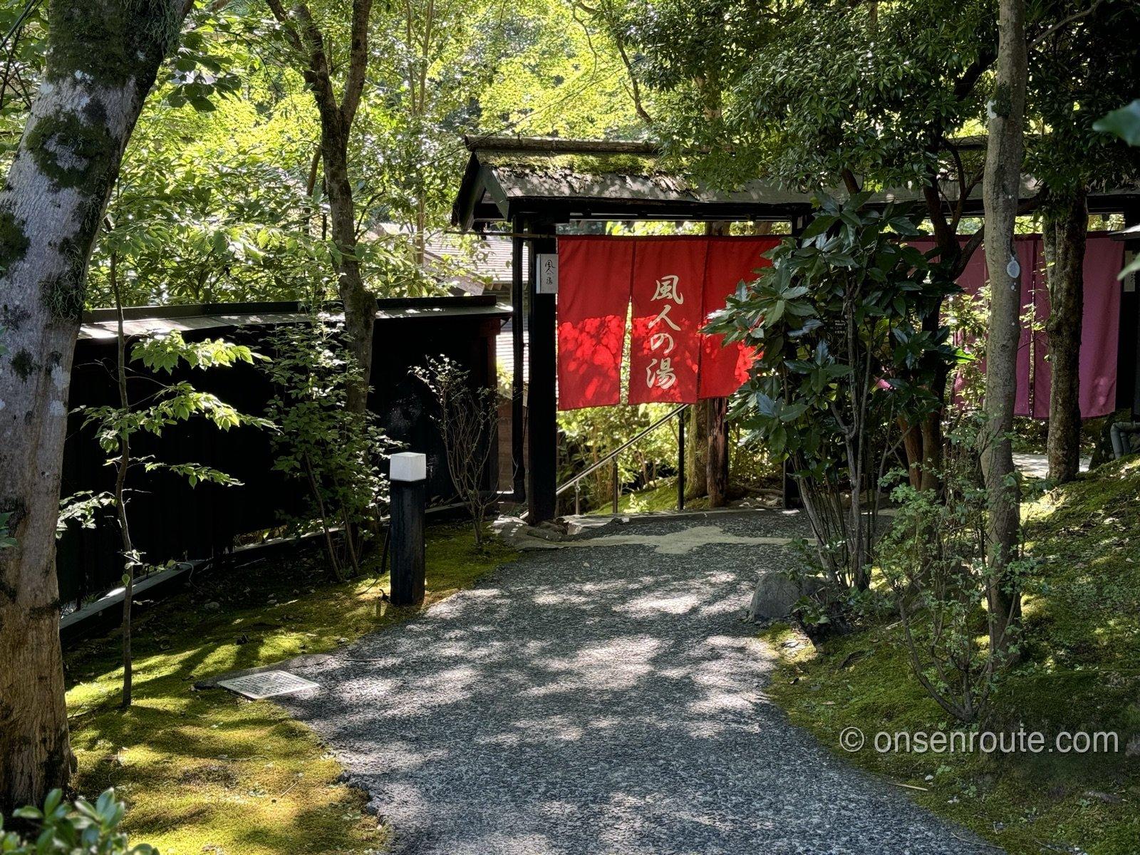 緑の小道の先に建つ湯小屋。赤い暖簾に風人の湯と書かれている
