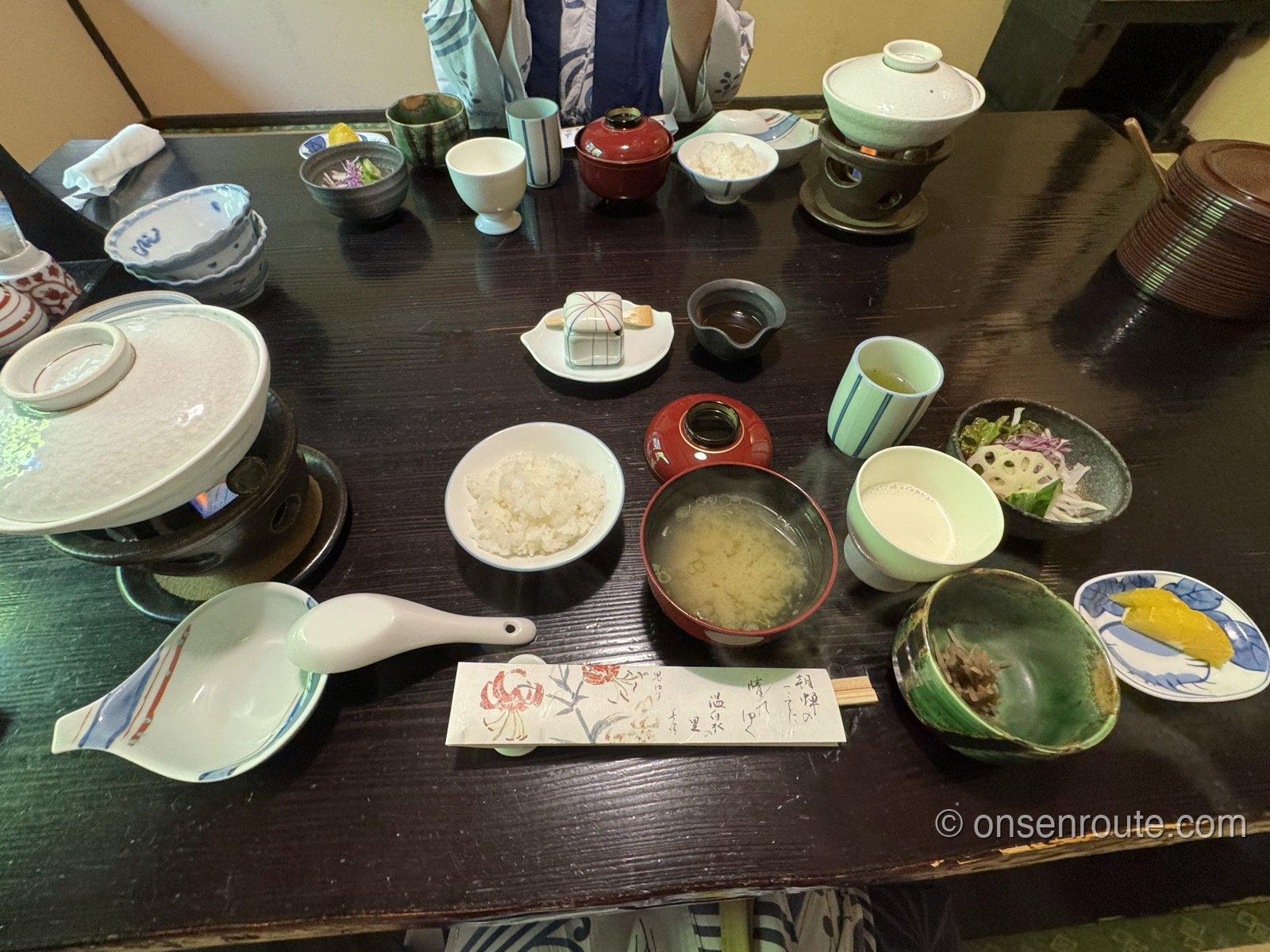 朝食の個室のテーブル。豆乳鍋、温かい牛乳、ご飯と味噌汁、小鉢が並ぶ