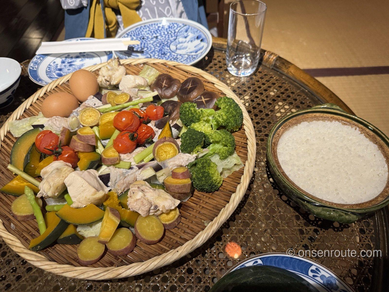 自炊した夕食。土鍋の白ご飯と、蒸し上がった海鮮と野菜の籠2つがテーブルに並ぶ