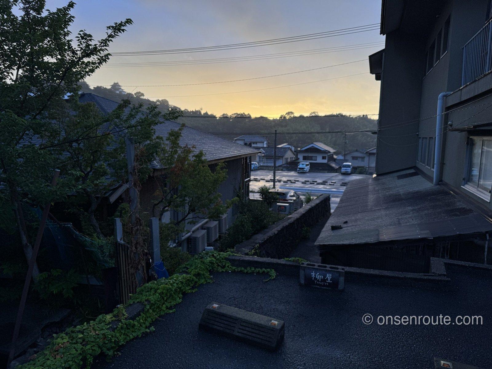柳屋の窓から見た鉄輪の朝焼け。湯けむりの向こうにオレンジ色の空と山のシルエットが広がる