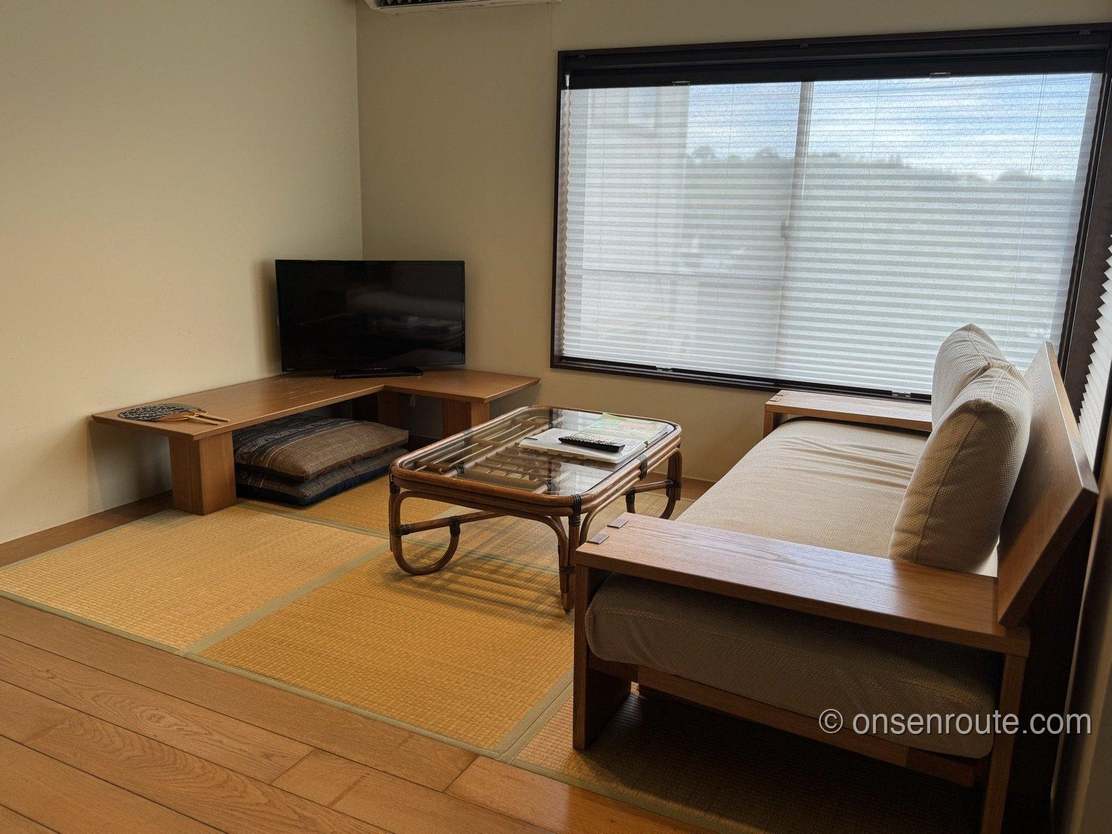 別のネストの部屋のリビング。大きな窓のそばに木のソファとラタンのローテーブルが置かれている