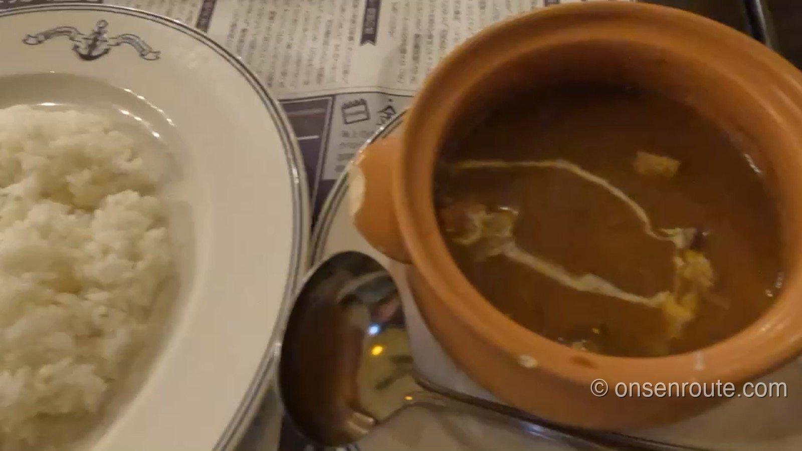 陶器の器に入った横須賀海軍カレーと、白いご飯の皿。スプーンが添えられている