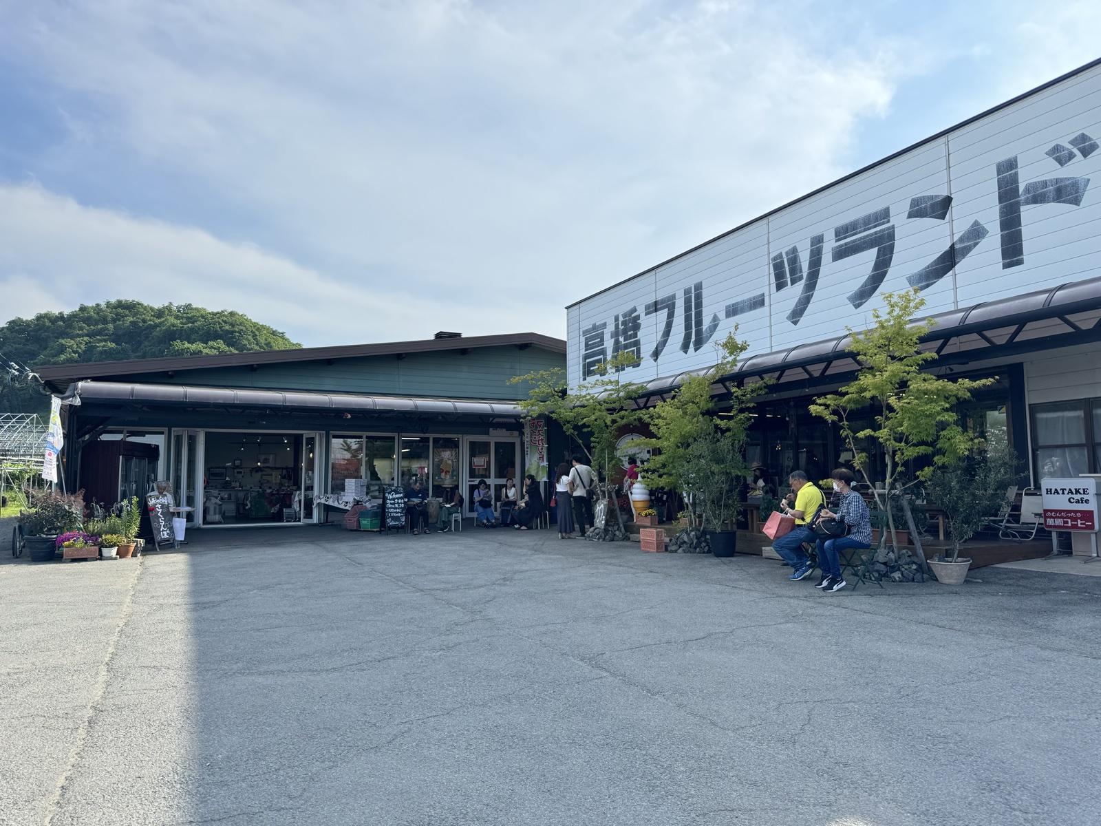 高橋フルーツランドの白い建物。大きな看板の下にHATAKE Cafeの入口が見える