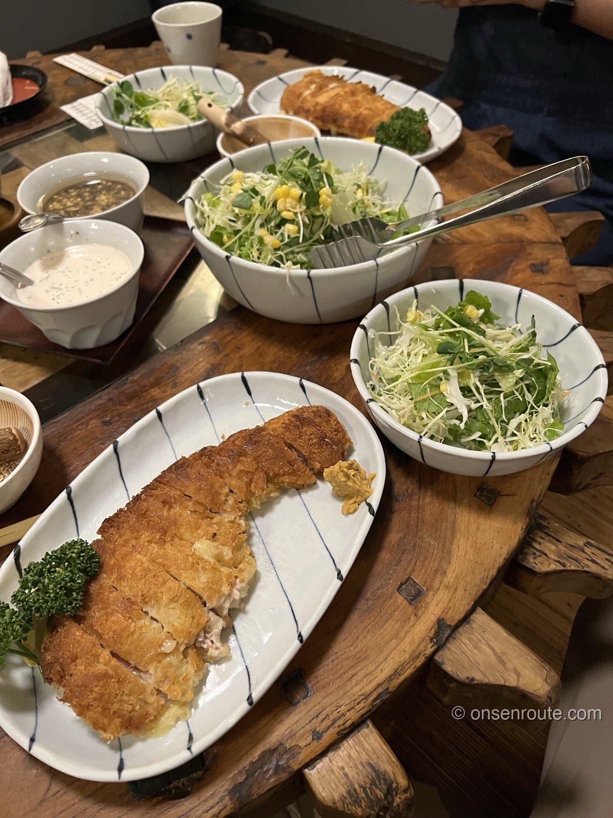 仁亭の焼きかつ定食 チーズ入りの焼きかつとサラダの大鉢が木のテーブルに並ぶ
