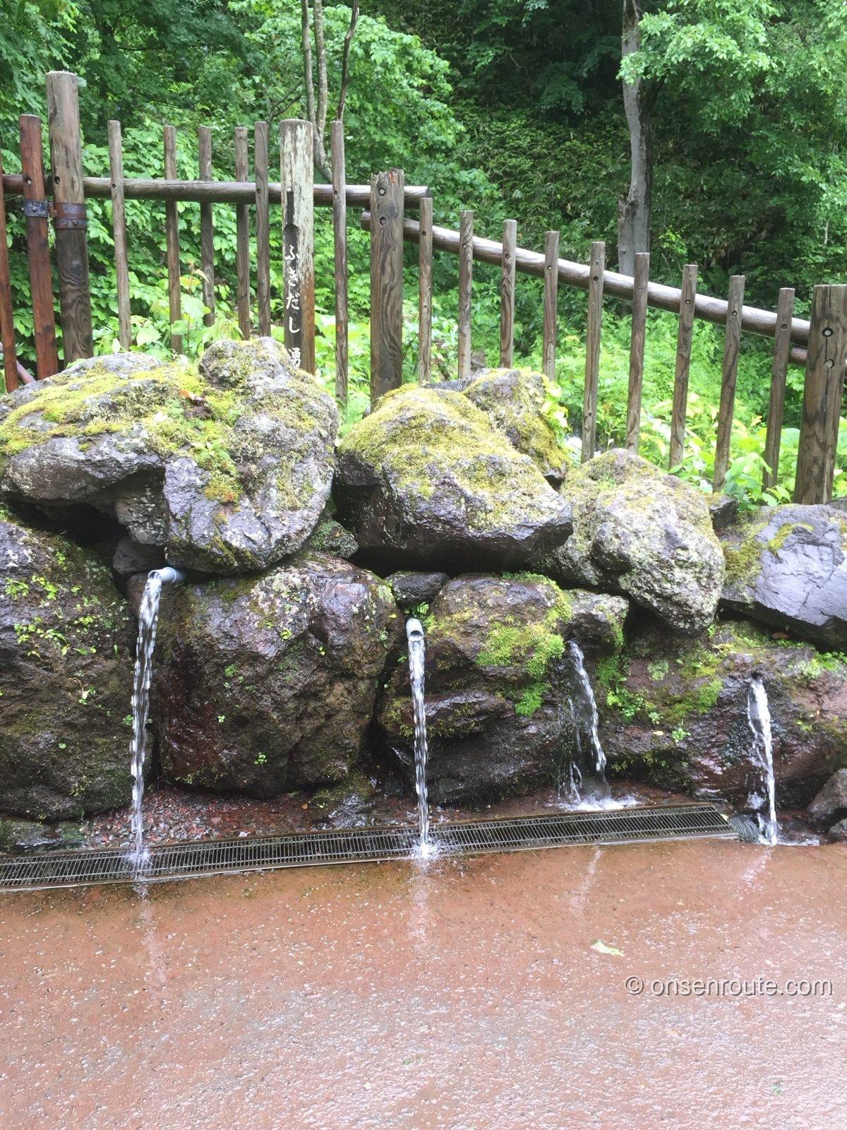 ふきだし公園の湧水汲み場。苔むした岩の間から何本もの湧水が流れ出している