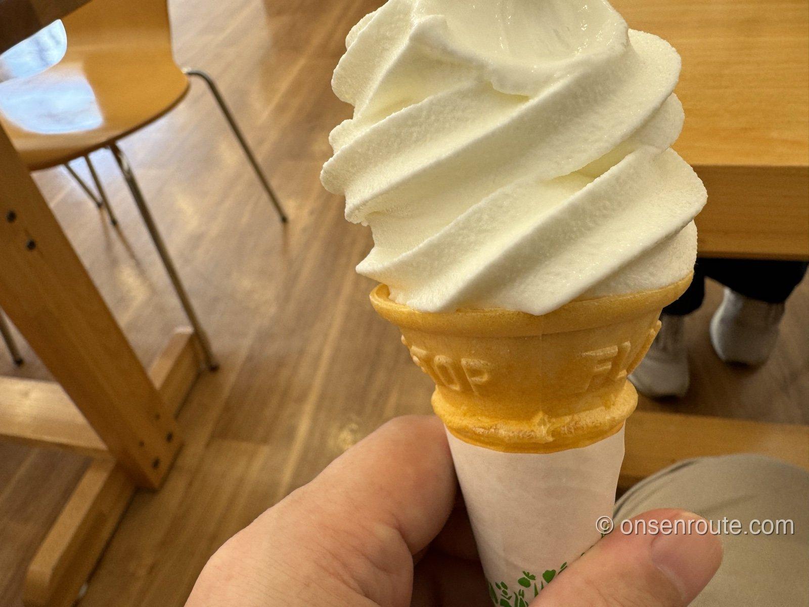 山中牧場のソフトクリーム。白いソフトが高く巻かれたコーンを手に持っている