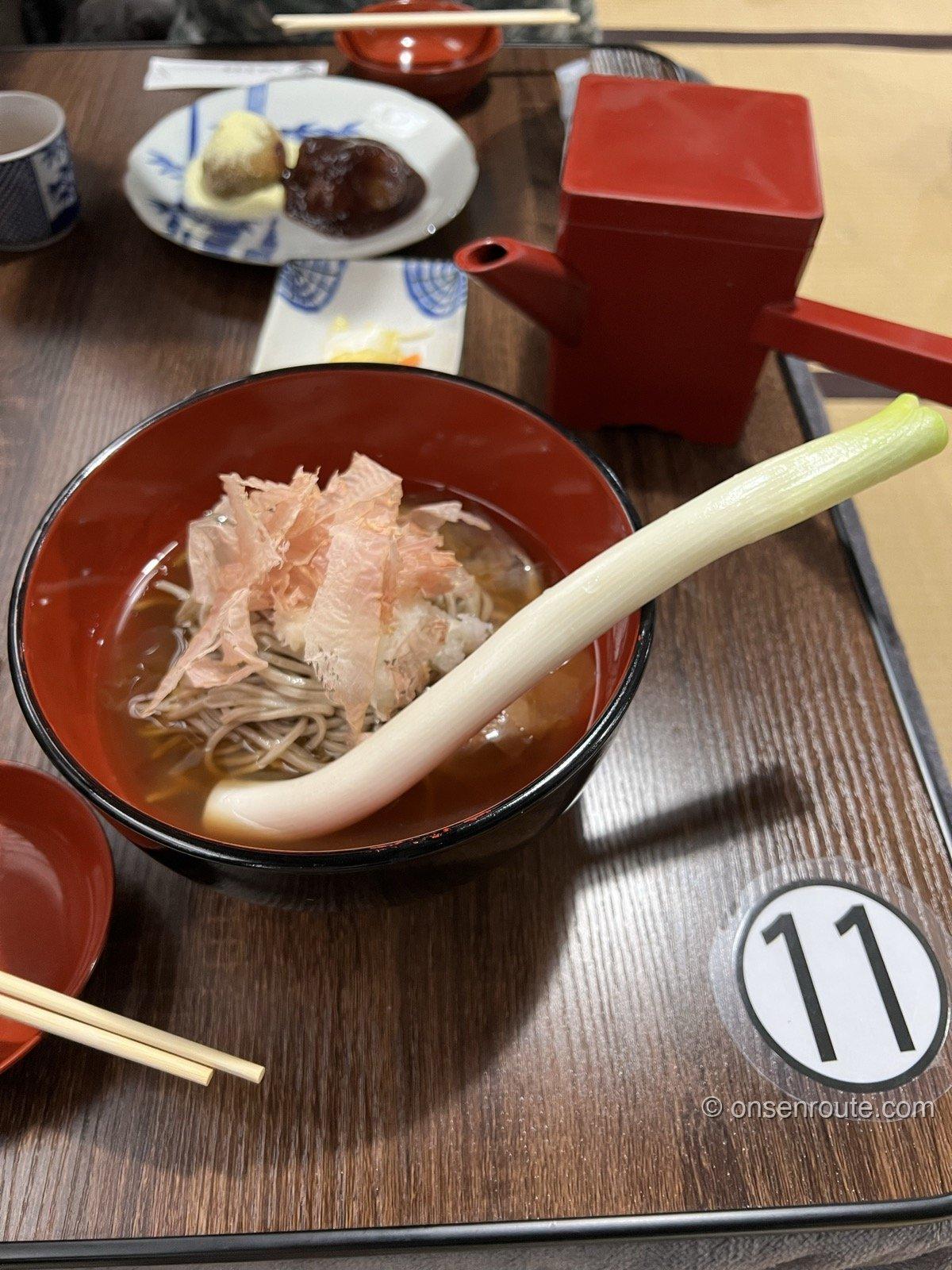 三澤屋の高遠そば 朱塗りの椀のそばに一本の長ネギが添えられている