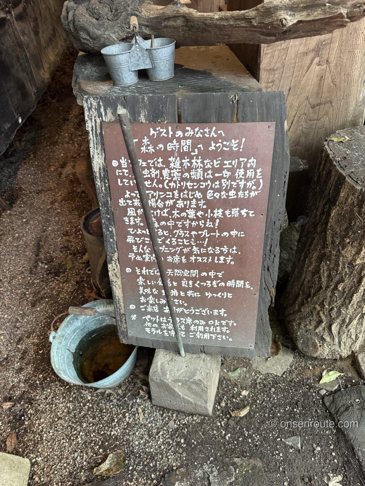 森の時間の入口に立つ手書きの案内看板