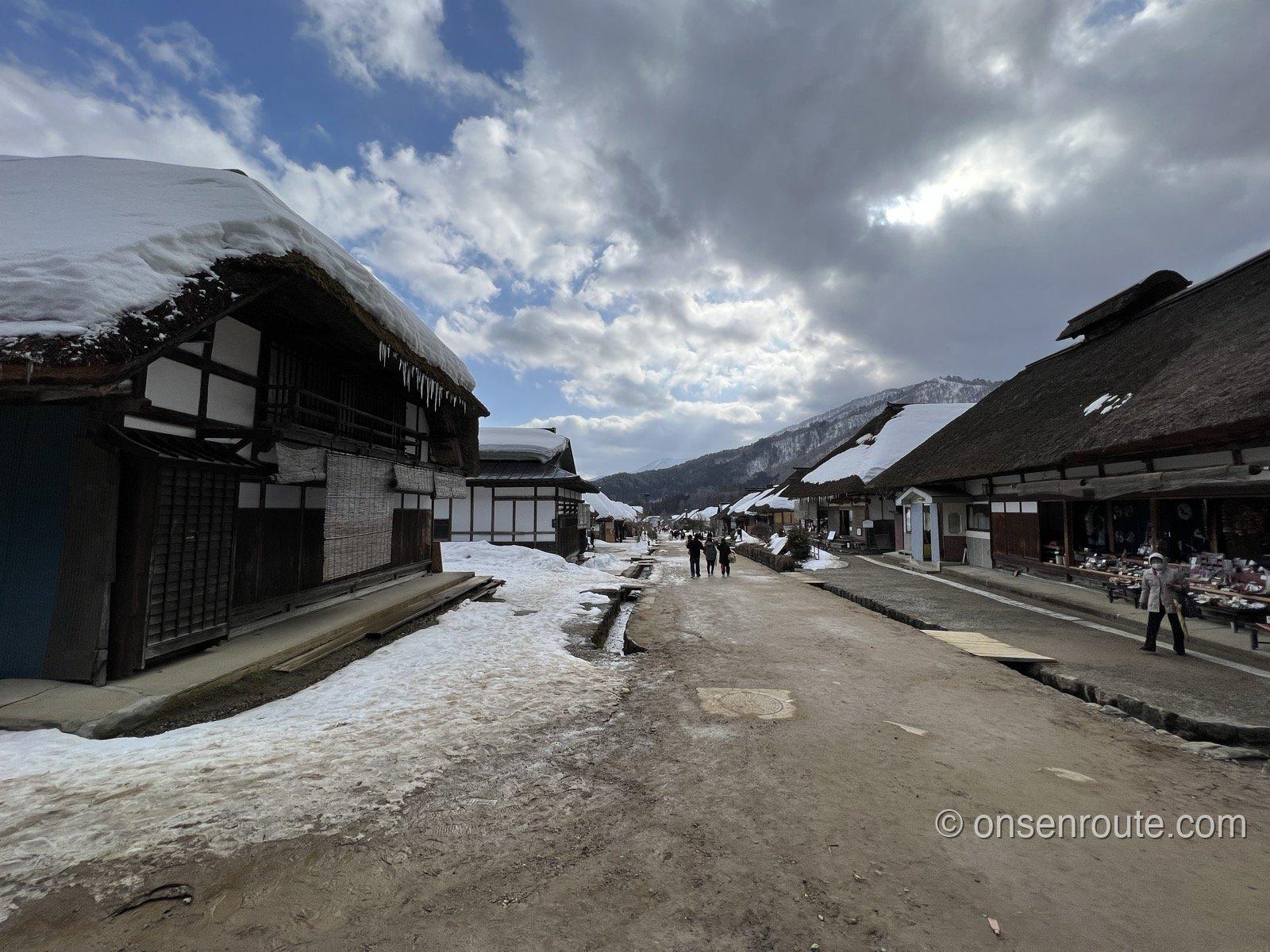 大内宿のメインストリート 両側に茅葺き屋根の民家が並ぶ雪解けの道