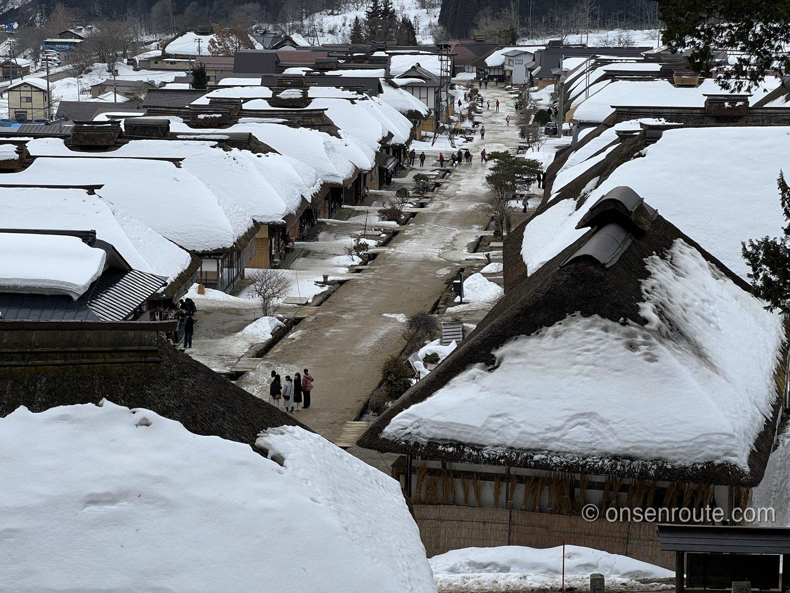 高台から見下ろす雪をかぶった大内宿の茅葺き屋根の家並み