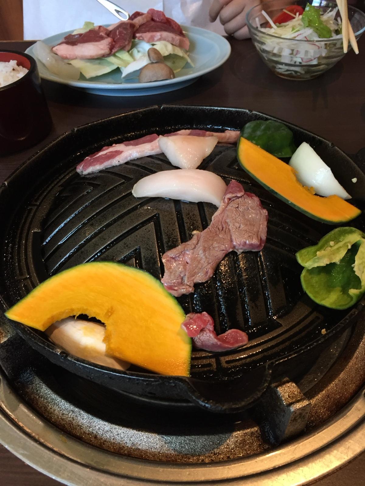 ジンギスカン鍋の上でラム肉とかぼちゃ、玉ねぎを焼いているところ