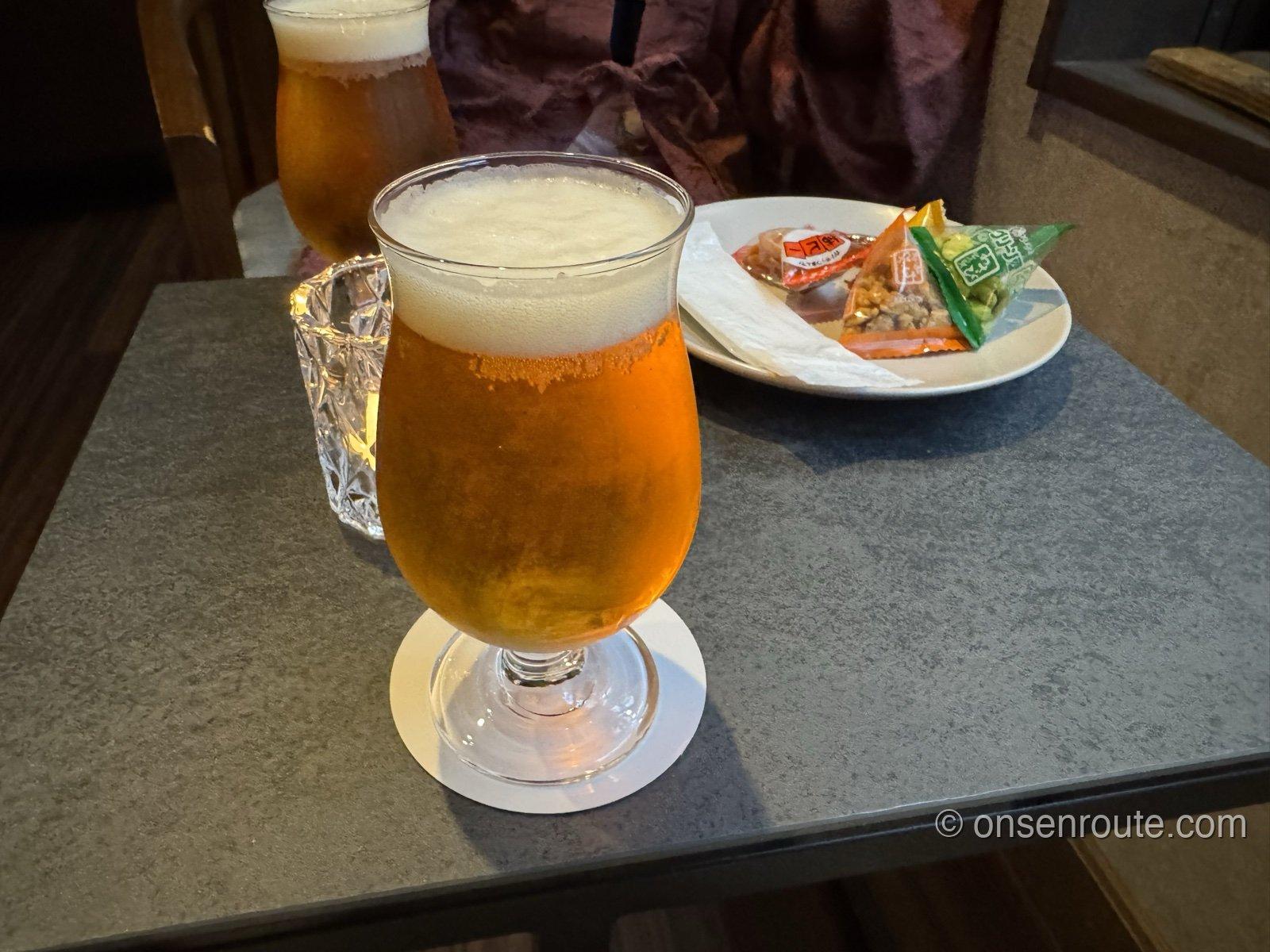 ラウンジ「Hêtre」のテーブルに注がれたビールが2杯。奥の皿にあられなどの小袋のおつまみ