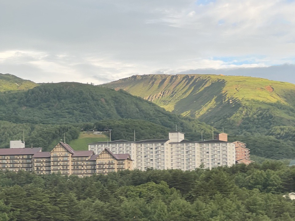 部屋の窓から見た草津の山並み。緑の森の向こうに山肌とリゾートマンション群が見える