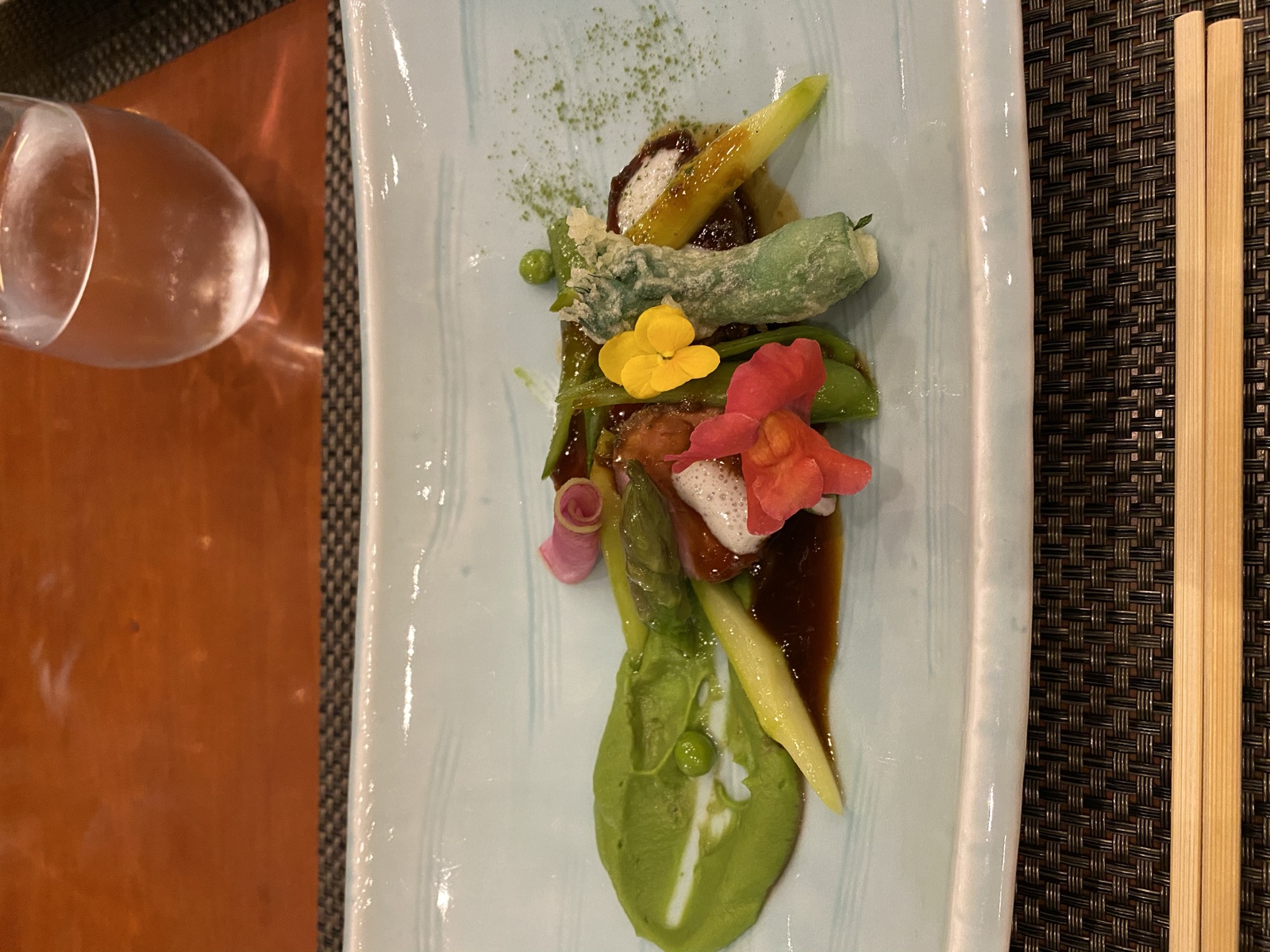 夕食のメイン料理。青い長皿にアスパラガスやエディブルフラワーが彩りよく盛り付けられている