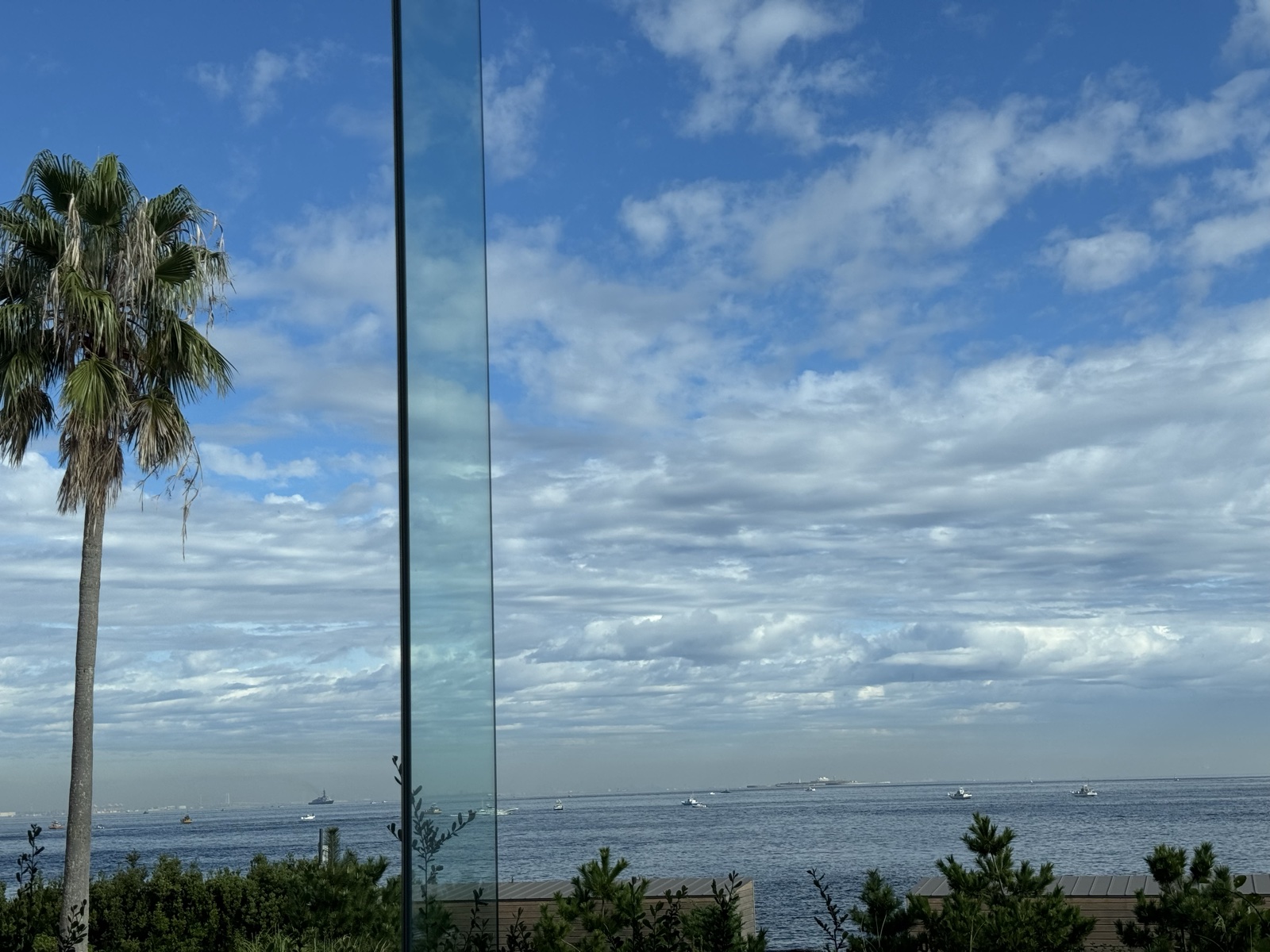ロビーからの東京湾の眺め。青空と雲、遠くに複数の船が見える