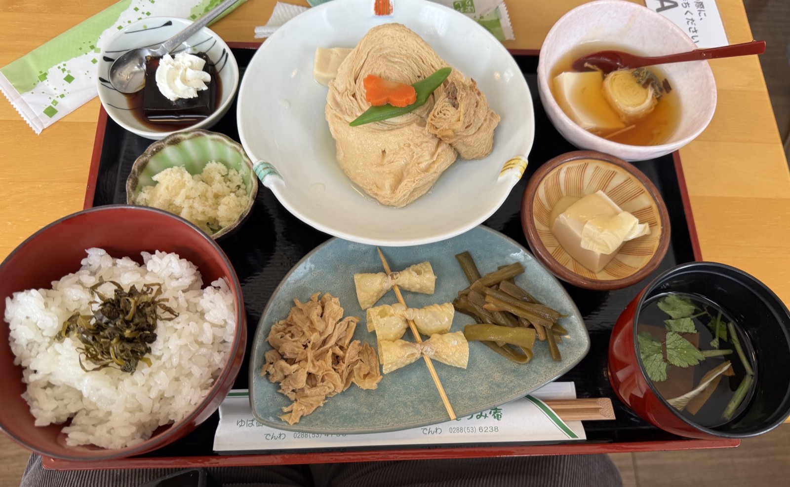 湯波御膳のお膳。福ゆばの煮物を中心に、ゆばの佃煮や串ゆば、酢の物など小鉢が並ぶ