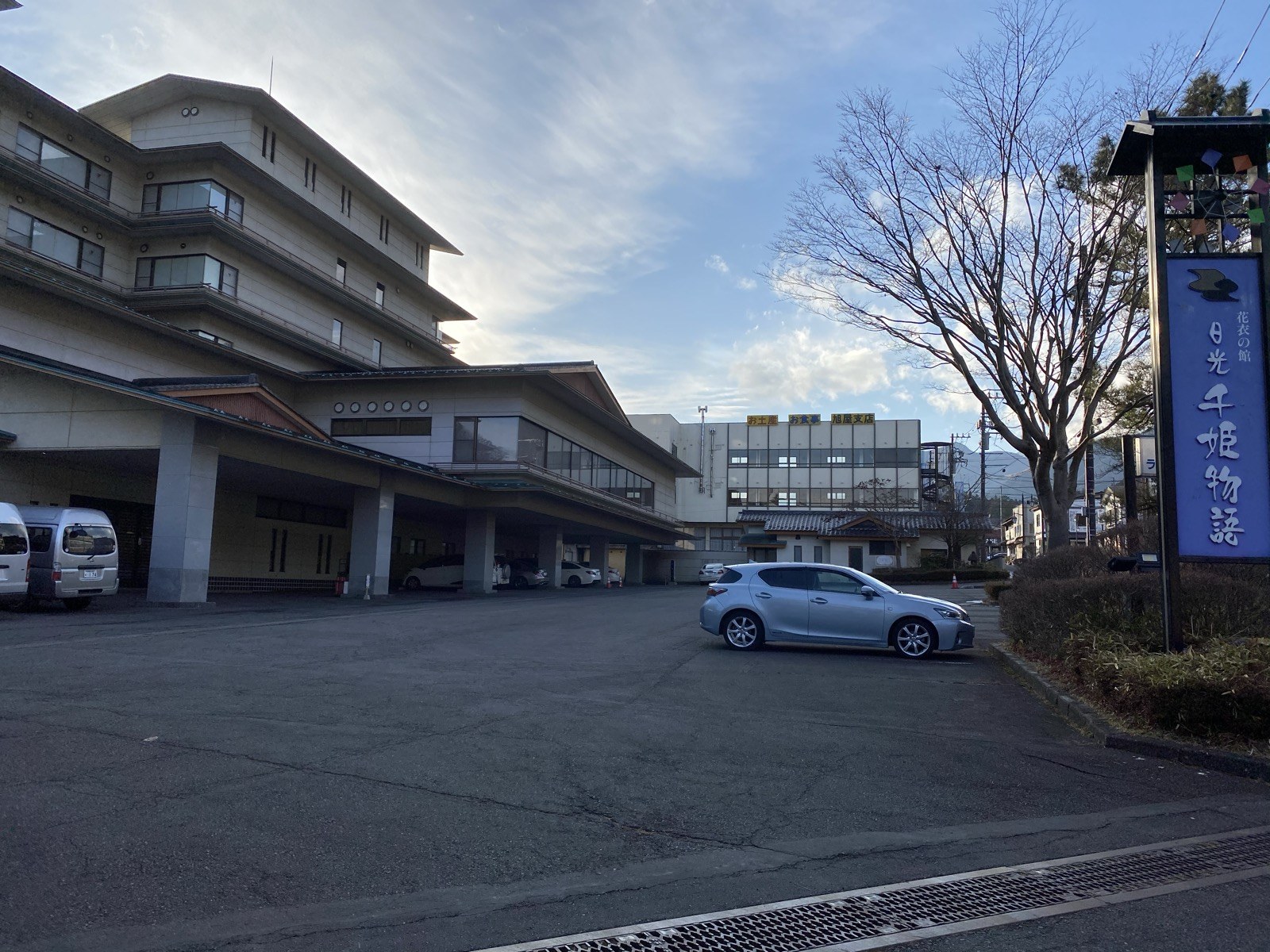 冬の朝の日光千姫物語の外観。「花衣の館 日光千姫物語」と書かれた看板と、車を停めた駐車場、葉の落ちた木が見える