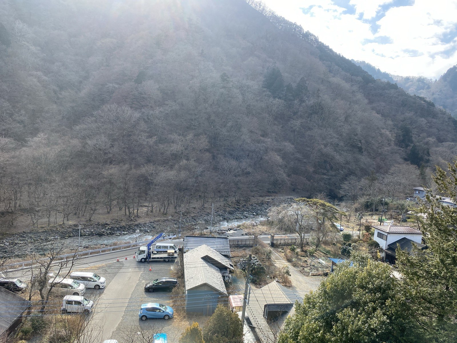客室の窓から見下ろす大谷川の渓谷。冬枯れの山肌と川、川沿いの道や家並みが見える