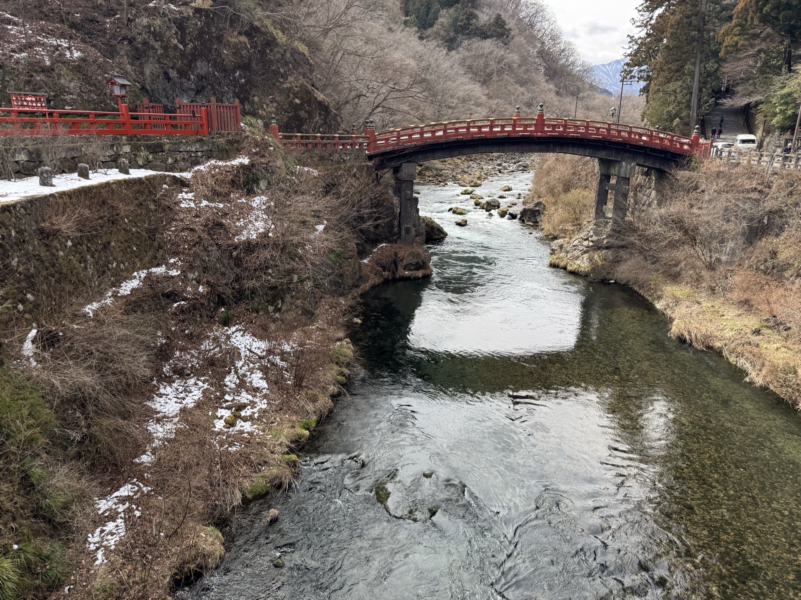 大谷川に架かる朱塗りの神橋。岸には雪が残り、渓流の水が澄んでいる