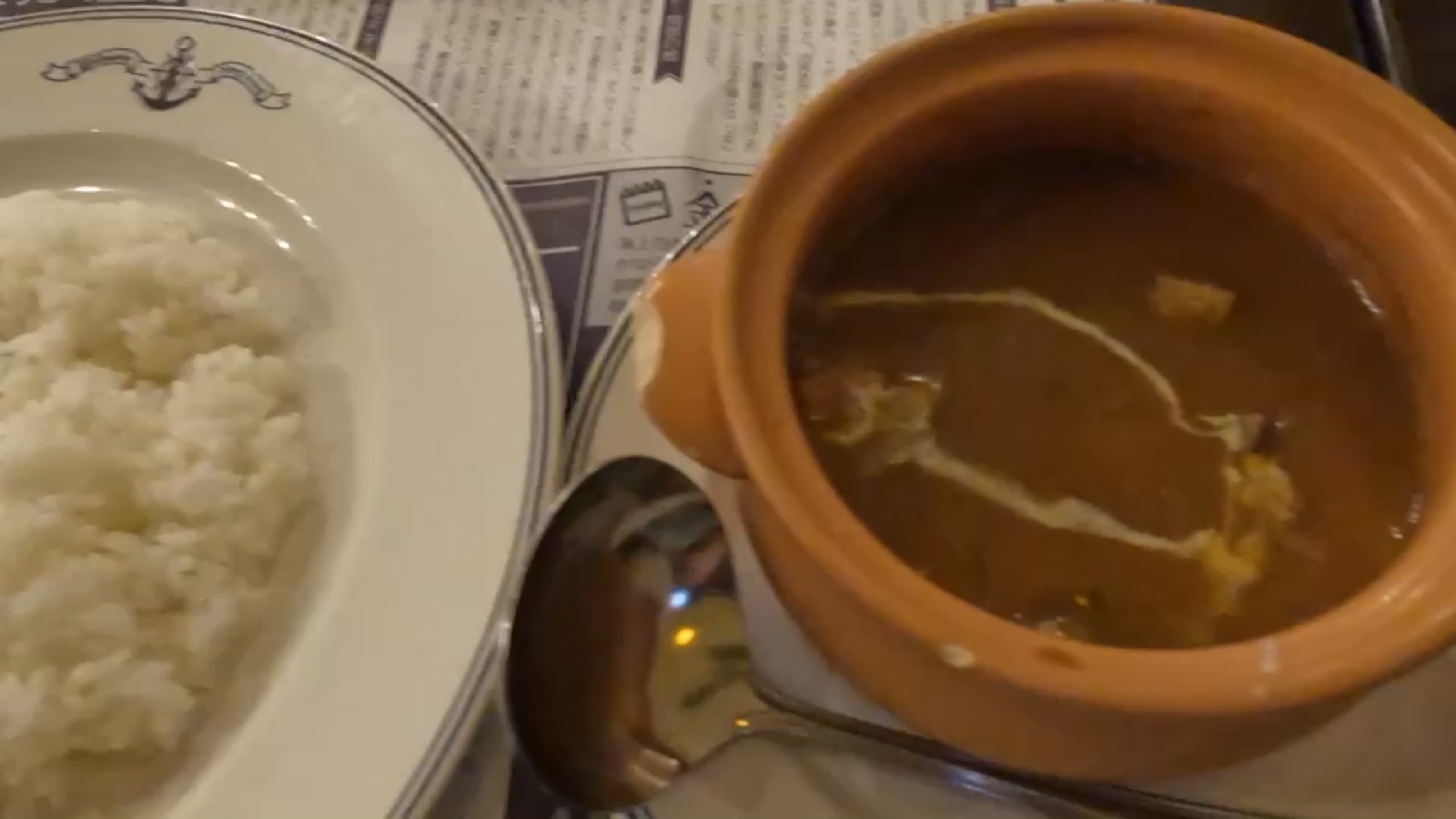 陶器の器に入った横須賀海軍カレーと、白いご飯の皿。スプーンが添えられている